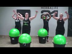 four women in black shirts are doing exercises on green exercise balls with their hands up