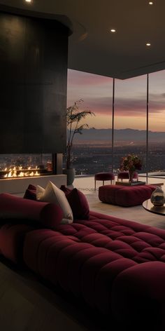 a living room with red couches and large windows overlooking the city at night time