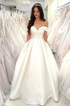 a woman is standing in front of some wedding dresses