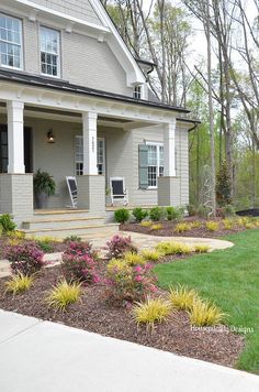 a house with landscaping in front of it and flowers on the side walk to the front door