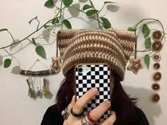 a woman taking a selfie with her cell phone wearing a crocheted hat