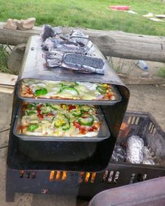 two pizzas cooking on top of an outdoor grill