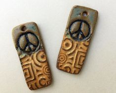 two metal tags with peace signs on them sitting next to each other in front of a white background