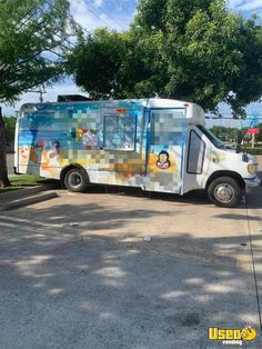 an ice cream truck is parked on the side of the road in front of some trees