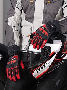 a man wearing a helmet and gloves sitting on a motorcycle