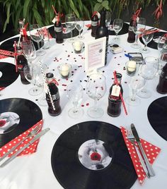 a table set up for a party with vinyl records and wine glasses on it, surrounded by red polka dot napkins