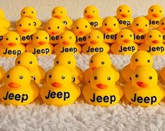 many yellow rubber ducks are lined up on a white carpet with the words jeep written in black