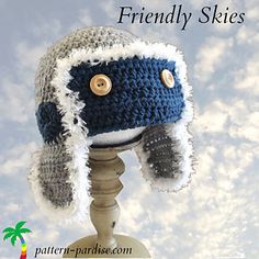 a crocheted hat with buttons on the front and side, sitting on top of a wooden stand