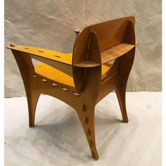 a wooden chair sitting on top of a white floor next to a gray wall with holes in it