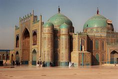 people standing in front of a large building with green domes on it's sides