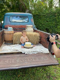 a baby sitting in the back of a truck with hay bales on it's bed