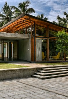 a modern house with large windows and steps leading up to the front door, surrounded by palm trees