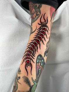 a man's arm with tattoos on it and an image of a scorpion in the background