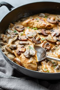 a skillet filled with chicken and mushroom gravy on top of a table