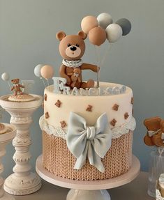 a teddy bear is on top of a baby's crib cake with balloons