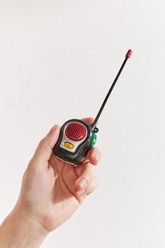 a hand holding a small radio in it's left side with a red antenna