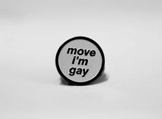 a black and white button with the words move i'm gay printed on it