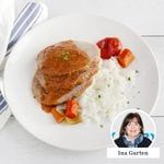 a white plate topped with meat, rice and veggies next to a woman