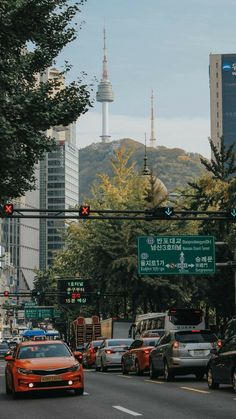 cars are stopped at an intersection in front of tall buildings and the sky scraper