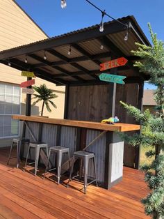 an outdoor bar with three stools under a roof