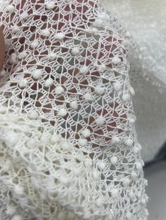 a woman's hand is holding a white lace shawl