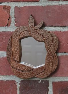 a mirror mounted to the side of a brick wall with a snake design on it