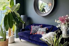 a living room filled with lots of plants next to a large mirror on the wall