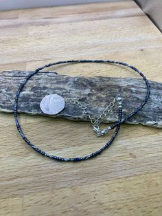 the blue beaded bracelet has a coin on it and is resting on a piece of wood