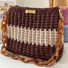 a crocheted purse sitting on top of a white table next to yarns