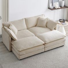 a large white couch sitting on top of a rug in a living room next to a window