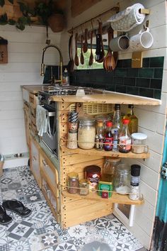 an outdoor kitchen with pots and pans hanging from the ceiling, next to a tiled floor