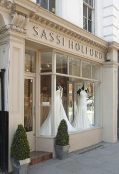 a store front with mannequins dressed in wedding gowns and dresses on display