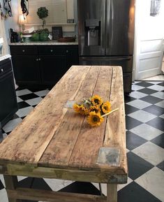 a wooden table with sunflowers on it in the middle of a black and white checkered floor