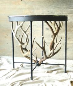 an antler's head is mounted on the side of a wooden table with metal legs