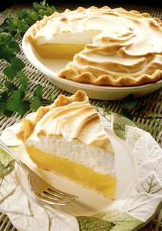 two pies sitting on top of white plates next to each other with green leaves