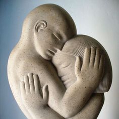 a sculpture of a woman holding a baby in her arms with both hands on it's chest