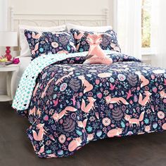 a bed with pink and blue comforters on top of it in a room next to a window