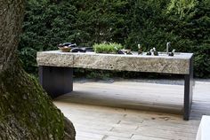 a bench made out of stone sitting on top of a wooden deck next to a tree