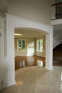 an empty living room with hard wood flooring and white columns on either side of the doorway