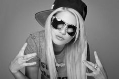 a woman with long blonde hair wearing sunglasses and a hat on her head is making the peace sign