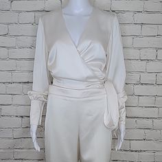 Karina Grimaldi Frieda Top In Ivory **Listed As A Jumpsuit; They Are In Fact Separate Pieces ** Top Is A Medium & Bottom Is A Small ** Measurements Below ** Silky Polyester Charmeuse Fabric Wrap Styling With Snap Button Tie Closure Flowy Long Sleeves Button Cuffs Coordinating Pant Pana Pant In Ivory Silky Polyester Charmeuse Fabric Flowy Wide Leg Pant Hits At Ankle Zips Up With A Hidden Back Zipper Closure Measurements: Top - Chest 34" Center Back 19" Outside Sleeve 26" Pant - Waist 30 1/2“ Front Rise 13“ Inseam 30“ Materials: Self 97% Polyester 3% Spandex Lining 100% Polyester Dry Clean Only Gently Worn - In Great Condition! Tags: Wrap Top, Blouse, Long Sleeves, C Elegant Cream Pants For Evening, Elegant Silk Fitted Jumpsuits And Rompers, White Long Sleeve Pantsuit For Spring, Silk Long Sleeve Pantsuit For Spring, Spring Silk Pantsuit With Long Sleeves, Cream Long Sleeve Sets For Workwear, Elegant Cream Pantsuit For Formal Occasions, Elegant Off White Sets For Spring, Elegant Fitted Cream Pantsuit