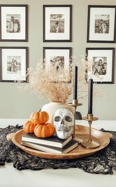 a tray with pumpkins, candles and pictures on the wall behind it in a dining room