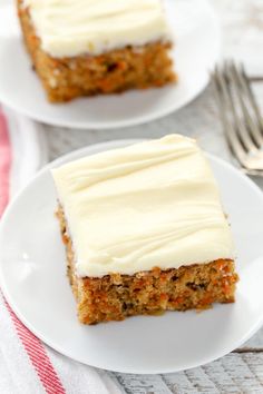 two white plates topped with carrot cake and frosting next to forks on a table