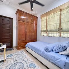 a bedroom with blue bedding and wooden closets in the corner, along with an area rug on the floor