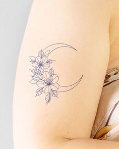 a woman with a flower tattoo on her left arm and the moon behind her back