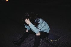 a woman sitting on top of a skateboard in the dark