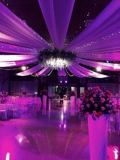 a room with purple lighting and white drapes on the ceiling, decorated with flowers