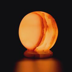 an orange object sitting on top of a wooden table next to a black background,