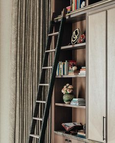 a ladder leaning up against a bookcase in a room with bookshelves and curtains