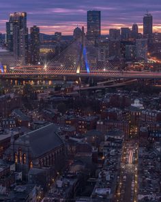 an aerial view of a city at night with the bridge in the foreground and buildings lit up